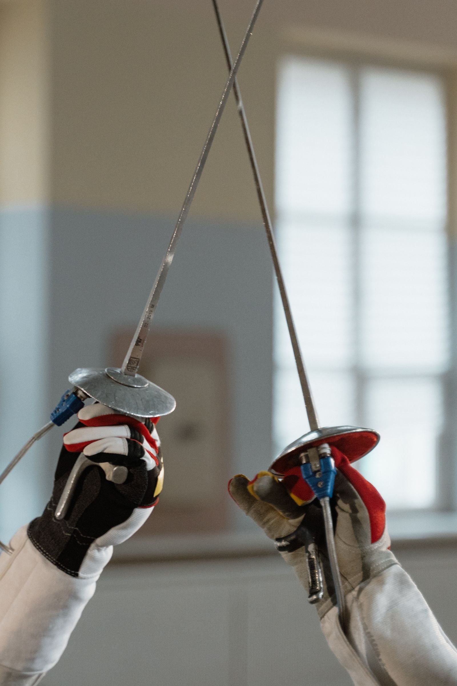 Two fencers' blades and bell-guards crossing, close.